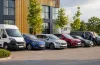 Uzņēmuma autoparks ar vairākām dienesta automašīnām pie moderna biroja ēkas, kas simbolizē pilna servisa līzingu un efektīvu autoparka pārvaldību.