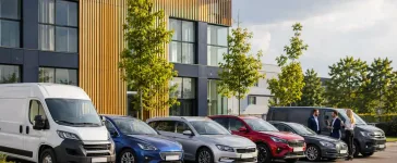 Uzņēmuma autoparks ar vairākām dienesta automašīnām pie moderna biroja ēkas, kas simbolizē pilna servisa līzingu un efektīvu autoparka pārvaldību.