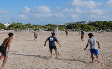Jaunieši spēlē futbolu smilšainā laukumā Klusā okeāna salā Nauru, kur futbols tikai sāk attīstīties.