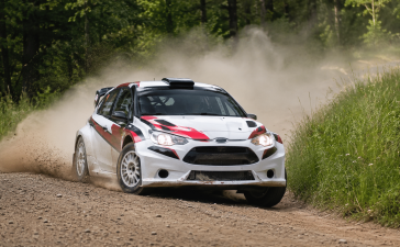 Rallija automašīna grants trasē Cesvaines apkārtnē sacensību laikā, paceļot putekļu mākoni.