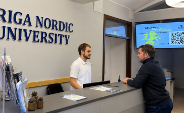 Rīgas Ziemeļvalstu augstskolas reģistratūra, kur apmeklētājs saņem informāciju par studiju iespējām.