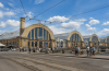 Rīgas Centrāltirgus Sakņu paviljons vasaras dienā ar cilvēkiem, tramvaja sliedēm un satiksmi pilsētas centrā.